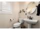 Charming powder room with pedestal sink, round mirror, and decorative accents for a stylish touch at 16565 W Garfield St, Goodyear, AZ 85338