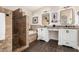 Bathroom with a walk-in shower with stacked-tile walls, soaking tub, and double sink vanity with espresso stained floors at 16565 W Garfield St, Goodyear, AZ 85338