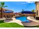 Beautiful backyard pool featuring a rock waterfall, lounge chairs, outdoor seating, and a lush green lawn at 16565 W Garfield St, Goodyear, AZ 85338