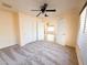 Spacious bedroom with neutral carpet, ceiling fan and closet, and view into other rooms at 17371 N 86Th Ave, Peoria, AZ 85382