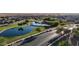 Aerial view featuring a neighborhood park with walking trails, a lake, and lush greenery at 17851 N Mughetto Dr, Maricopa, AZ 85138