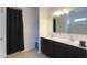 Well-lit bathroom with dual sinks, dark cabinets, and a shower-tub combo behind a black curtain at 17851 N Mughetto Dr, Maricopa, AZ 85138