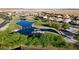 Aerial view of a community pond and playground with lush landscaping and walking paths at 17851 N Mughetto Dr, Maricopa, AZ 85138