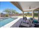 Inviting backyard with a covered patio, sparkling pool, and stylish outdoor furniture for relaxing and entertaining at 18000 W Thistle Landing Dr, Goodyear, AZ 85338