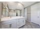 Bathroom featuring double sink vanity, large mirror, and walk-in shower at 18000 W Thistle Landing Dr, Goodyear, AZ 85338