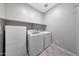 Functional laundry room features a washer, dryer, and shelving for organized storage at 18000 W Thistle Landing Dr, Goodyear, AZ 85338