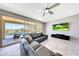 Stylish living room with tile floors, ceiling fan, and a view of the backyard pool area through large sliding glass doors at 18000 W Thistle Landing Dr, Goodyear, AZ 85338