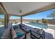 Covered patio leading to a luxurious outdoor pool with comfortable seating and mountain views at 18000 W Thistle Landing Dr, Goodyear, AZ 85338