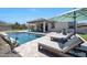 Inviting backyard with a sparkling pool, lush landscaping, and comfortable lounge chairs at 18000 W Thistle Landing Dr, Goodyear, AZ 85338