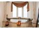 Close-up of a luxurious soaking tub with travertine surround and column accents at 18425 W Santa Irene Dr, Goodyear, AZ 85338