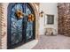 Close-up of the arched double front doors decorated with seasonal fall wreaths and stone accents at 18425 W Santa Irene Dr, Goodyear, AZ 85338