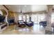 Spacious living room with a stone fireplace, plush sofas, a piano, and large windows offering a scenic view at 18425 W Santa Irene Dr, Goodyear, AZ 85338