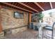 Relaxing outdoor space with stacked stone walls, decorative columns, and a mounted TV at 18425 W Santa Irene Dr, Goodyear, AZ 85338