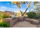 Charming outdoor kitchen area with built-in grill, counter, and seating beneath a mature shade tree at 22063 N 77Th St, Scottsdale, AZ 85255