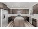 Open kitchen features dark wood cabinets, quartz counters, an island, and stainless steel appliances at 22500 N Greenland Park Dr, Maricopa, AZ 85139