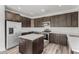 Open kitchen features dark wood cabinets, quartz counters, an island, and stainless steel appliances at 22500 N Greenland Park Dr, Maricopa, AZ 85139