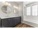 Bright bathroom featuring a double vanity, round mirrors, and a tub under a window at 2363 W Dusty Wren Dr, Phoenix, AZ 85085