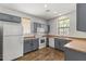 Efficient kitchen layout with gray cabinets, laminate countertops, and white appliances, complemented by wood-look flooring at 2363 W Dusty Wren Dr, Phoenix, AZ 85085