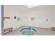 Indoor community hot tub featuring tiled trim, benches, coat rack, and posted rules at 3345 E University Dr # 47, Mesa, AZ 85213