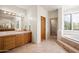 Spacious main bathroom boasts double sinks, wood cabinets, a soaking tub, and walk-in shower with natural lighting at 41503 N 109Th Pl, Scottsdale, AZ 85262