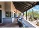 Covered patio with stone flooring, comfortable lounge furniture, and desert views at 41503 N 109Th Pl, Scottsdale, AZ 85262