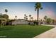 Charming single-story home featuring a well-manicured lawn, palm trees, and desert landscaping at 5333 E Sheena Dr, Scottsdale, AZ 85254