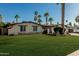 Inviting home featuring a well-kept lawn, desert landscaping, and mature palm trees at 5333 E Sheena Dr, Scottsdale, AZ 85254