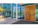 A modern building entrance features a sleek wood door and a glass facade, set against a backdrop of lush greenery at 5455 E Lincoln Dr # 1004, Paradise Valley, AZ 85253
