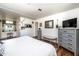 Bright bedroom featuring a makeup vanity, a neutral bench, and a television on a gray dresser at 632 S 83Rd Way, Mesa, AZ 85208