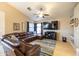 An open-concept living room featuring a ceiling fan, a TV, and a comfortable leather sectional sofa at 7463 E Monte Ave, Mesa, AZ 85209