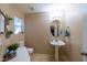 Powder room with pedestal sink, decorative mirror, lighting, and toilet at 7463 E Monte Ave, Mesa, AZ 85209