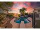 Sparkling swimming pool with diving board, surrounded by lush greenery under a vibrant sunset sky at 7463 E Monte Ave, Mesa, AZ 85209