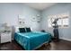 Comfortable bedroom with a stylish blue bedspread, hardwood floors, and natural light at 8601 E De La O Rd, Scottsdale, AZ 85255