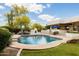 Beautiful pool with a water feature, surrounded by lush landscaping, and an outdoor fireplace at 8601 E De La O Rd, Scottsdale, AZ 85255