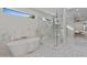 This primary bathroom has a free-standing tub, marble lined shower, and a window above the tub at 9820 N 87Th Pl, Scottsdale, AZ 85258