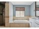 Bright bathroom featuring soaking tub, travertine tile surround, large window, and view of large shower at 10450 E Terra Dr, Scottsdale, AZ 85258