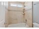 Neutral toned bathroom with white tub, tan tile surround, a window, and a shower fixture at 10450 E Terra Dr, Scottsdale, AZ 85258