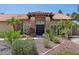 Elegant single-story home featuring a stone accent entryway, double wooden doors, and beautiful desert landscaping at 10450 E Terra Dr, Scottsdale, AZ 85258