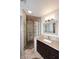 Modern bathroom with walk-in shower featuring glass block, decorative mirror, and vanity with sink at 11007 N 26Th St, Phoenix, AZ 85028