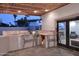 Outdoor kitchen with a built-in grill, prep area, and access to a cozy indoor seating space at 11007 N 26Th St, Phoenix, AZ 85028