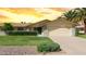 Charming single-story home featuring a two-car garage, desert landscaping, and lush green lawn at 12711 W Omega Dr, Sun City West, AZ 85375