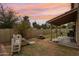 A spacious backyard featuring lush grass, a covered patio, and play equipment at dusk at 1344 N Brittany Ln, Gilbert, AZ 85233