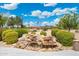 Picturesque backyard waterfall feature surrounded by lush landscaping and mature trees at 15502 W Agua Linda Ln, Surprise, AZ 85374