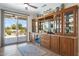 Charming custom bar area with cabinetry, a wine rack, beverage fridge, and access to the patio at 15502 W Agua Linda Ln, Surprise, AZ 85374