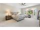 Spacious bedroom with plush carpet, ceiling fan, and large windows with outdoor views at 15502 W Agua Linda Ln, Surprise, AZ 85374
