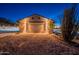 Exterior of desert home featuring garage with ample lighting at twilight at 15612 S Tuthill Rd, Buckeye, AZ 85326