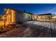 Rear exterior of desert home features a charming bridge and stairs leading up to the house, illuminated at twilight at 15612 S Tuthill Rd, Buckeye, AZ 85326