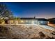 Rear exterior of desert home with patio and desert vegetation at twilight at 15612 S Tuthill Rd, Buckeye, AZ 85326