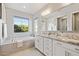 Well-lit bathroom with dual vanities, granite countertops, a large window, and soaking tub at 1941 W Yellowstone Way, Chandler, AZ 85248