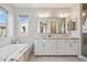 Elegant bathroom featuring double sinks, a large mirror, and a separate soaking tub and shower at 1941 W Yellowstone Way, Chandler, AZ 85248
